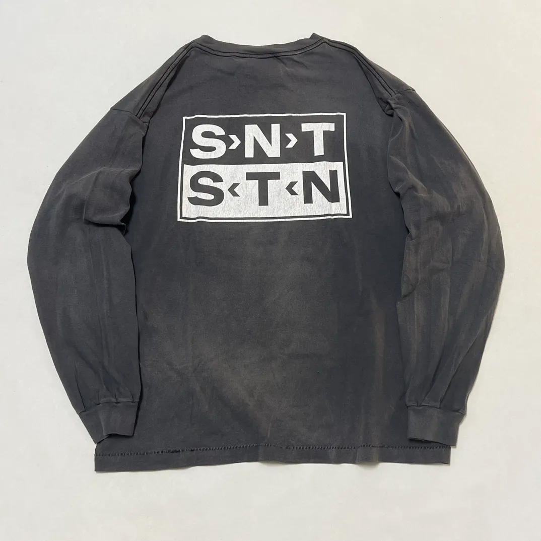 SAINT Mxxxxxx S>N>T LS TEE/BLACK Autumn and winter new style S>N>T slogan crack printed long TEE, washed black S-XL Asut ready-made garments dyed, the whole piece sprayed with horse-hair spray, and then sprayed again to fade the color. The collar and cuffs are frayed. Many hangings are worn NEW VINTAGE. Heavy craftsmanship.